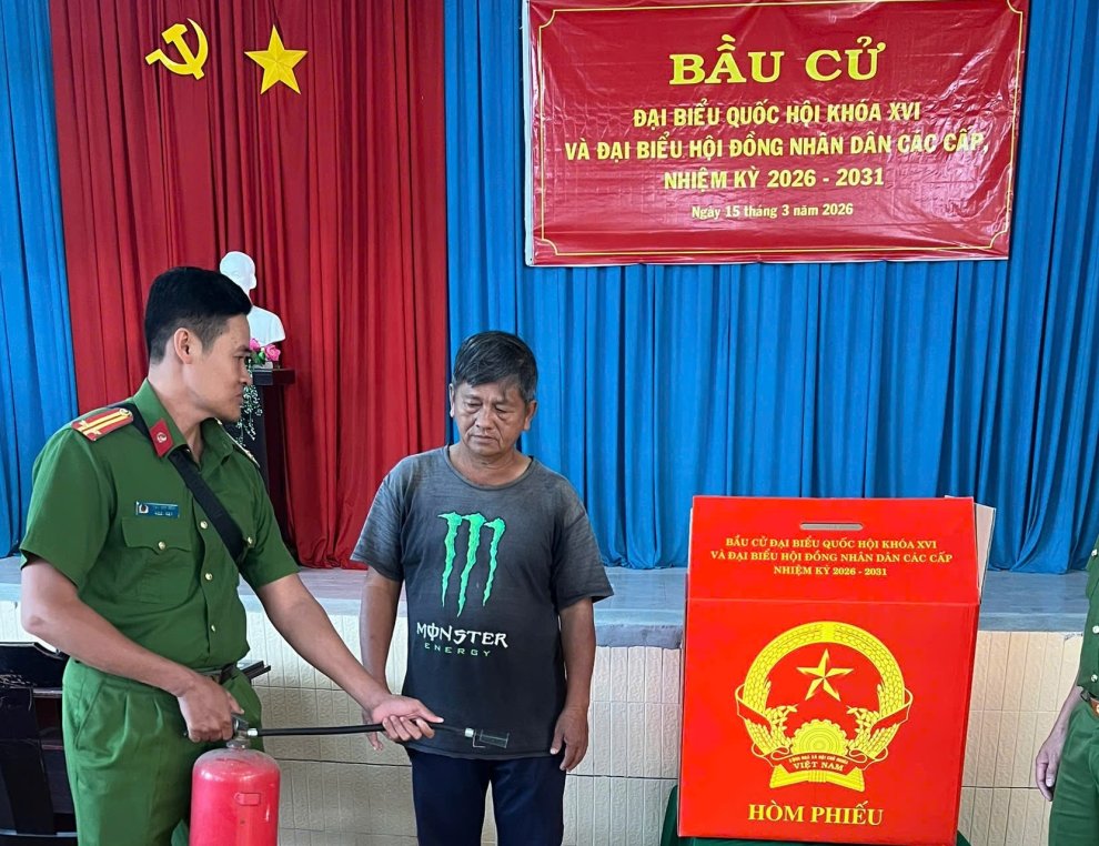Ảnh thành viên Tiểu ban ANTT xã hướng dẫn thành viên tổ bầu cử sử dụng thiết bị PCCC