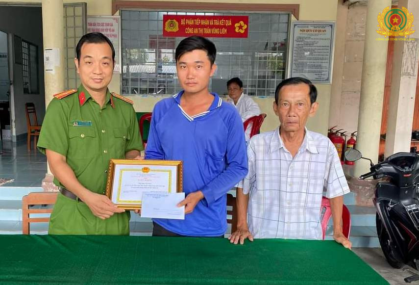 Đại diện Công an thị trấn Vũng Liêm, chính quyền địa phương thừa ủy quyền của Chủ tịch UBND huyện Vũng Liêm trao giấy khen của Chủ tịch UBND huyện cho anh Phan Chí Thảo