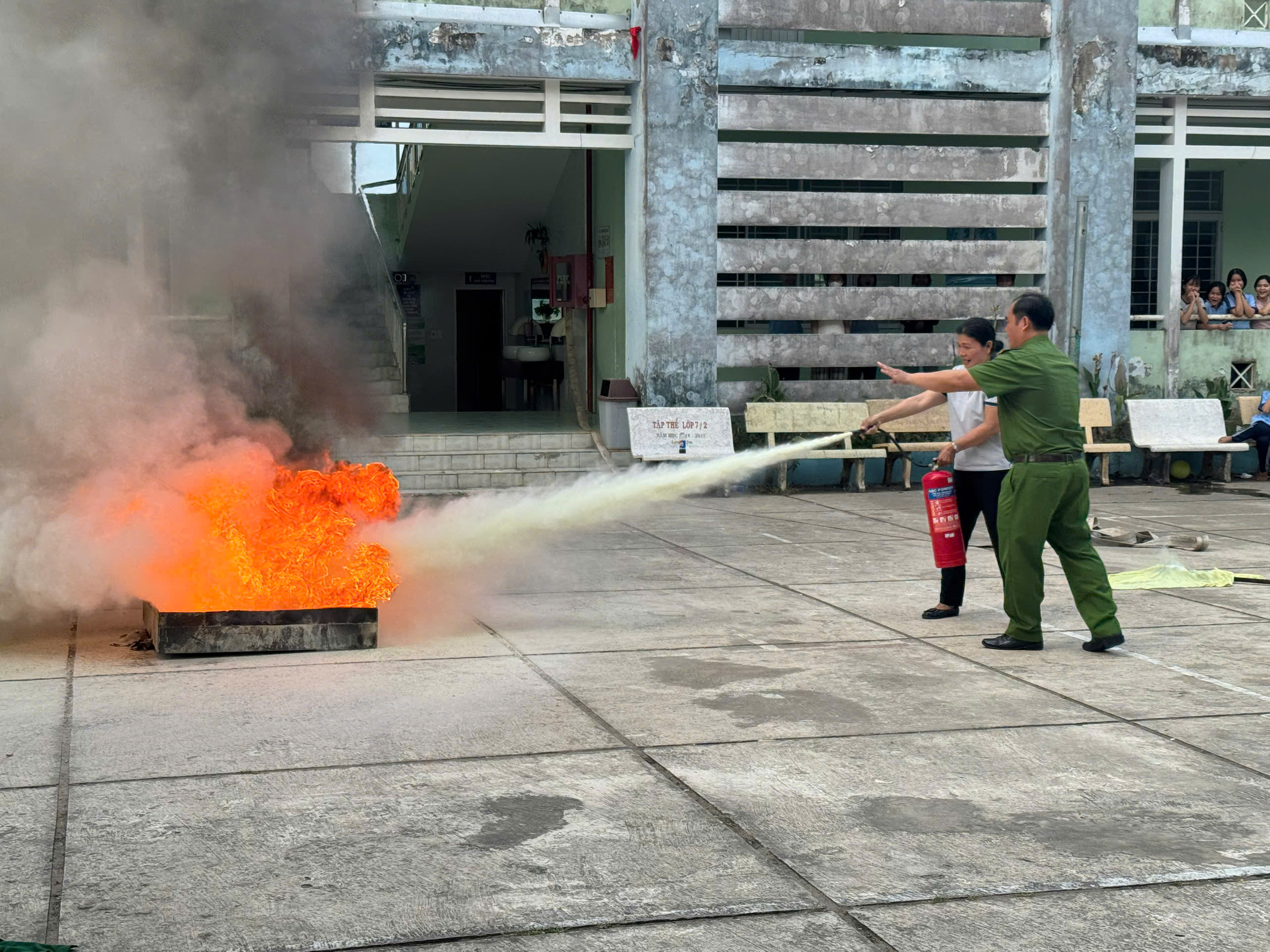 giáo viên nhà trường thực hành sử dụng bình chữa cháy dập tắt đám cháy